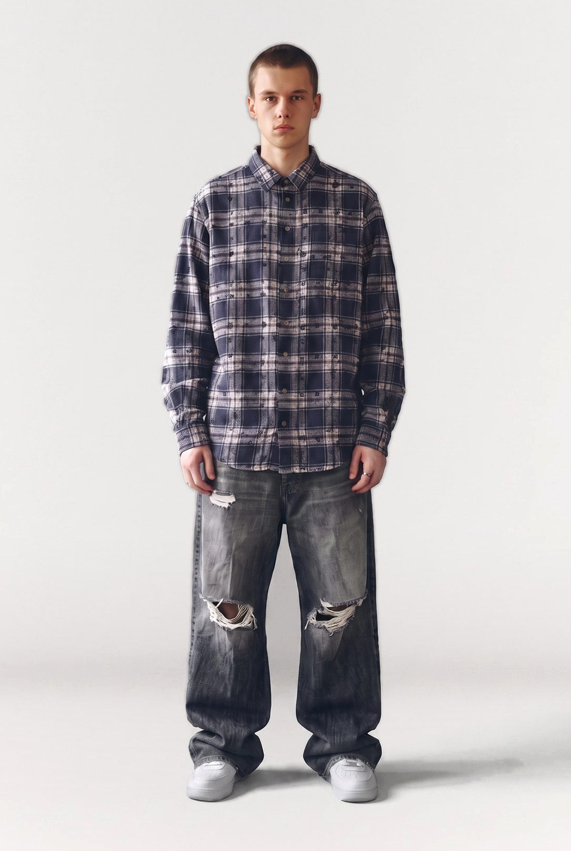 Man in an oversized plaid flannel shirt and distressed baggy jeans, full figure studio shot