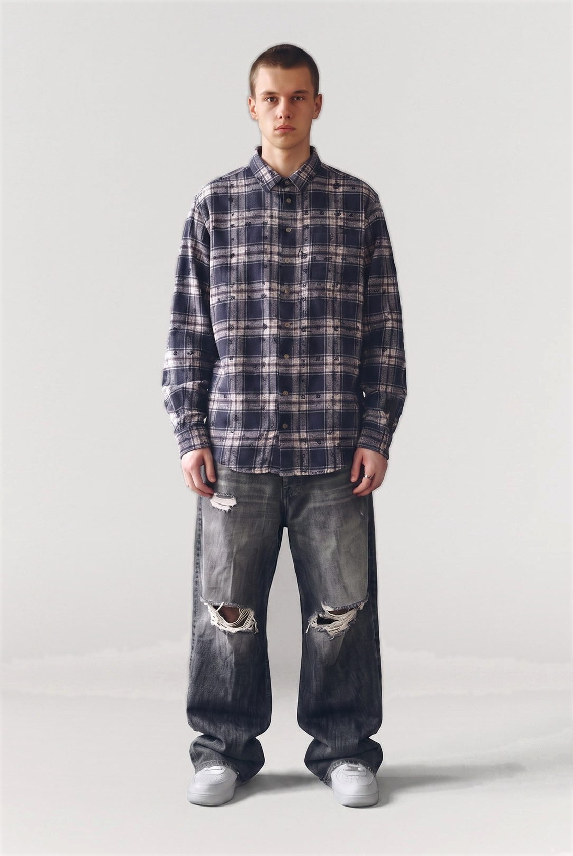 Man in an oversized plaid flannel shirt and distressed baggy jeans, full figure studio shot